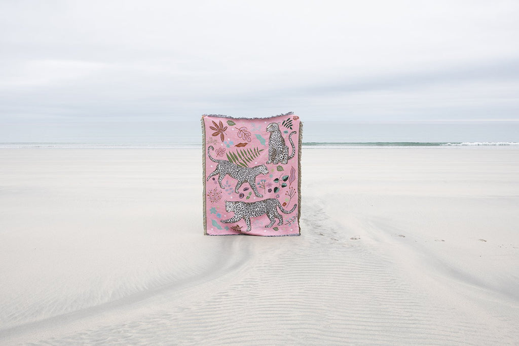 Snow Leopard blanket held up on a beach