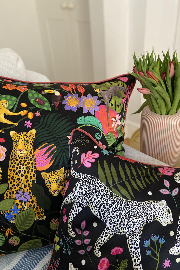 At home photo of two silk cushions on a white sofa and tulips on a side table